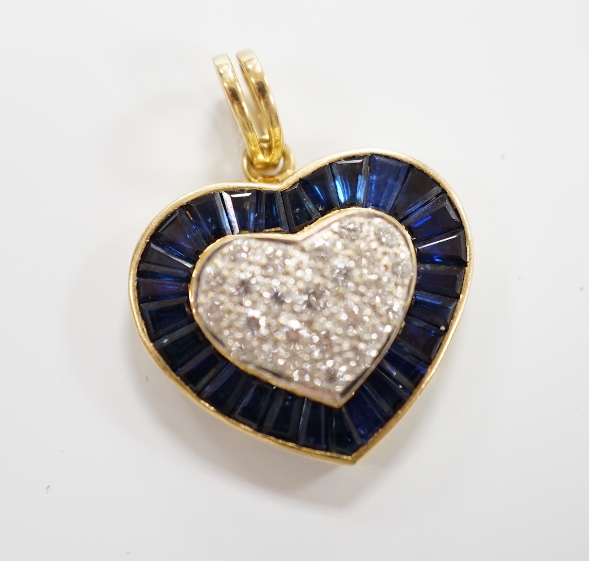 A modern 18k, pave set sapphire and diamond heart shaped pendant, overall 25mm, gross weight 4.9 grams.